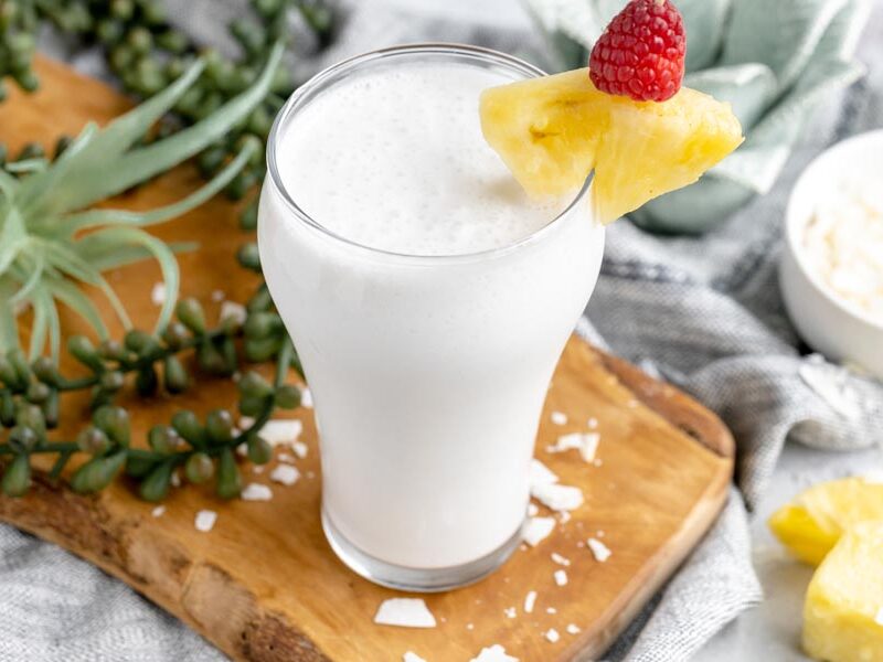 a tropical smoothie with pineapples around and coconut flakes scattered