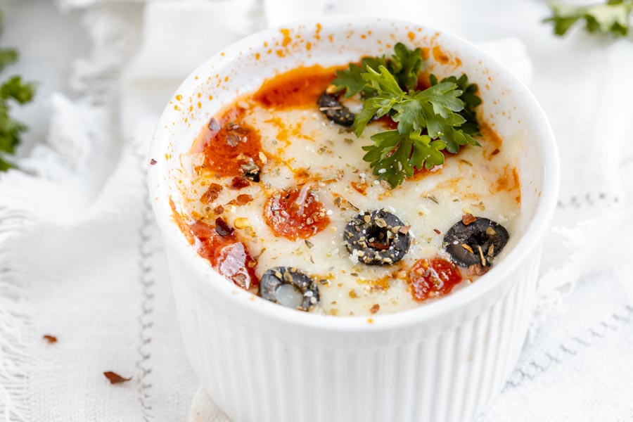 a ramekin with cheesy pizza in it topped with parsley and italian seasoning