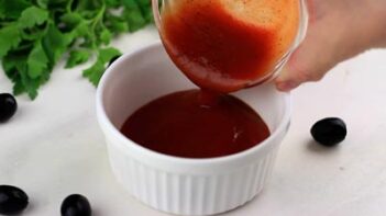 pouring red marinara sauce into a ramekin