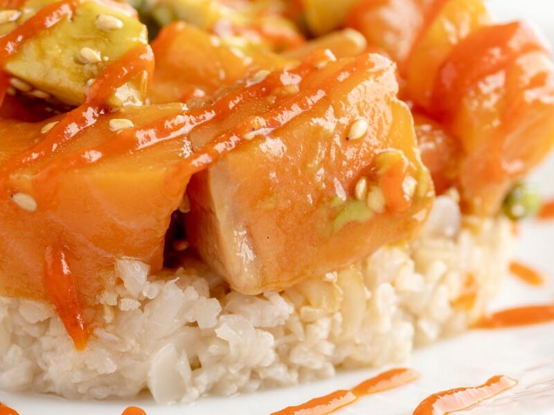 a salmon poke bowl with sesame seeds over white rice