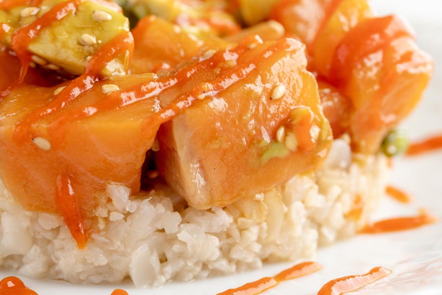 a salmon poke bowl with sesame seeds over white rice