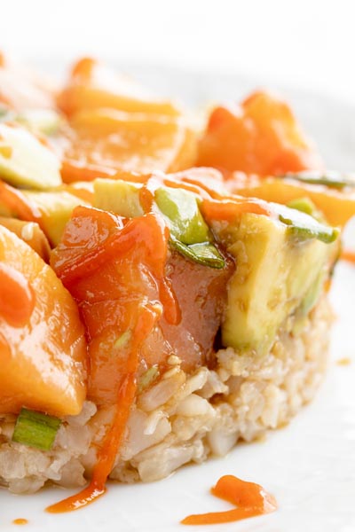 close up view of salmon poke and avocado on top of rice