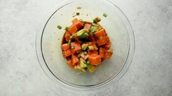 a bowl with diced salmon, avocado, green onion and soy sauce in it