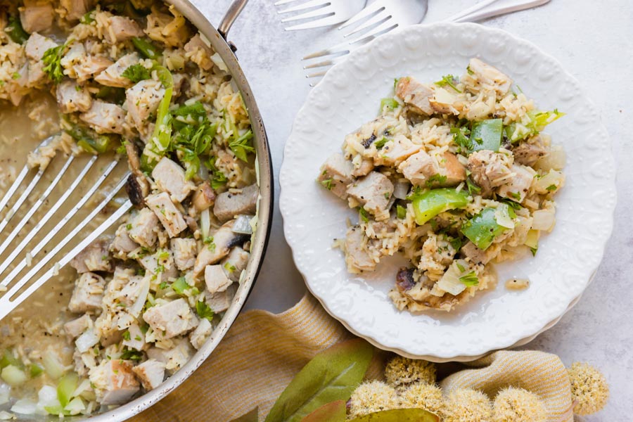 a plate with pork and rice dinner next to a skillet