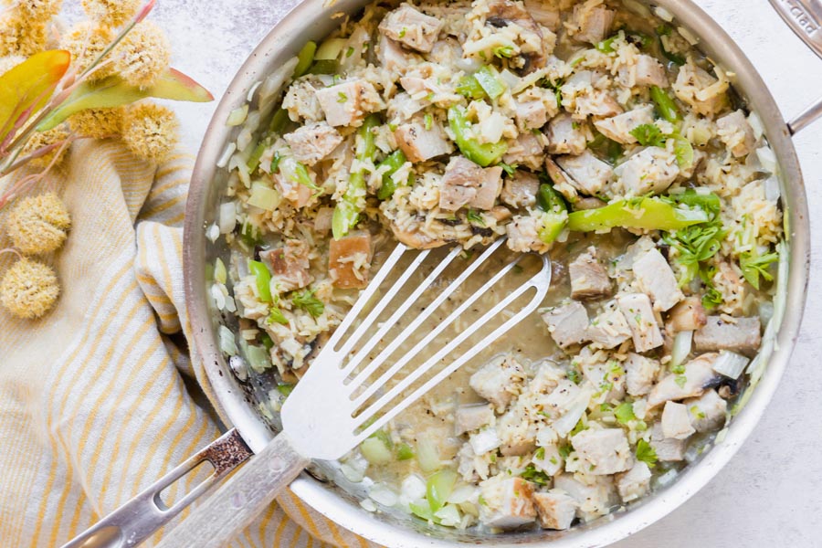 a skillet with a stir fry of pork, vegetables and rice