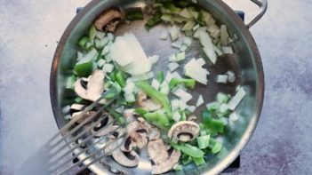 onion bell pepper and mushroom cooking in a skillet