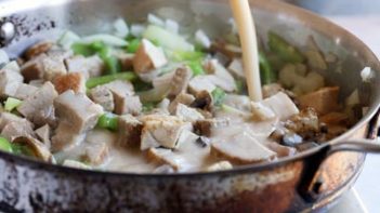 pouring a creamy mushroom sauce on a stir fry skillet