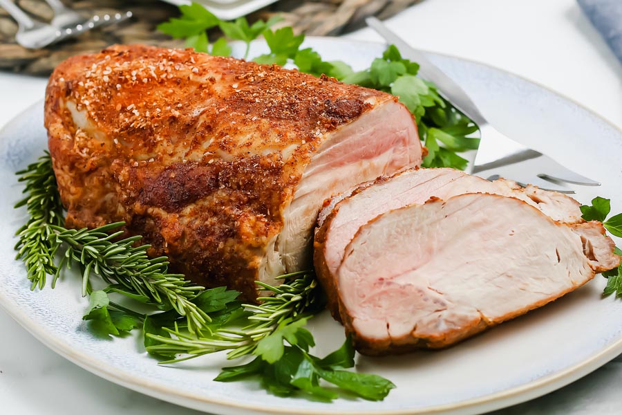 a dinner main course of pork roast on a platter with greens