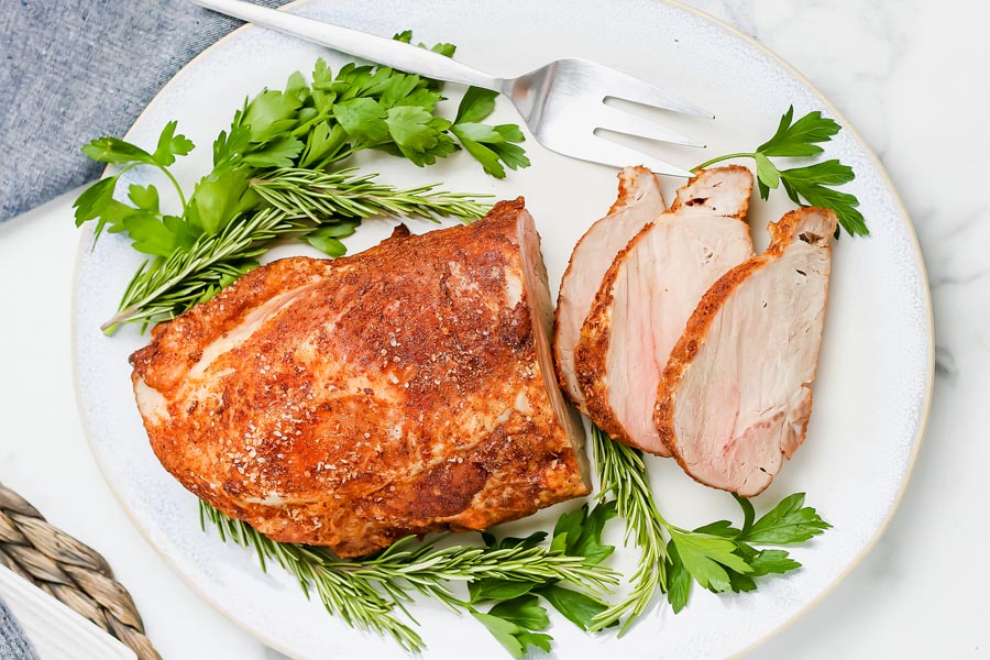 a dry paprika rub on a pork roast with parsley and rosemary on the plate