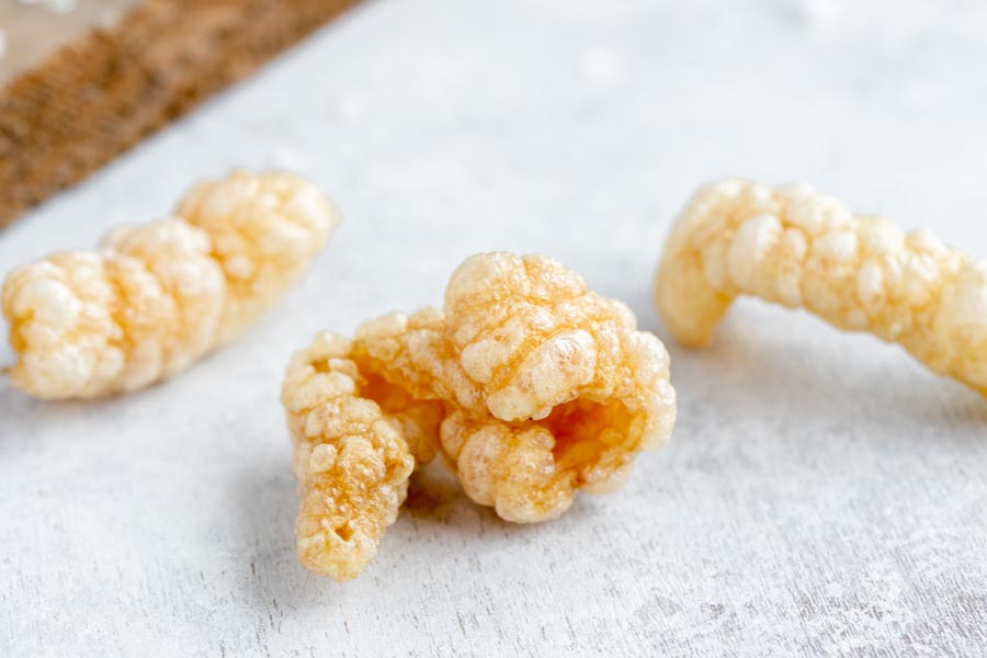 Close up of three pork rinds to show how light, airy and crispy they are.