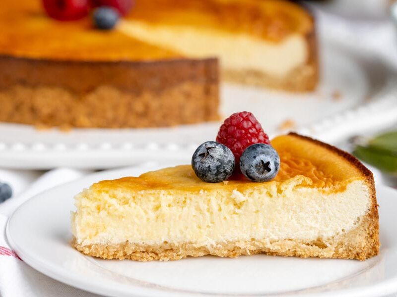 A slice of creamy cheesecake on a plate topped with berries.