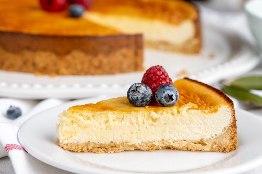 A slice of creamy cheesecake on a plate topped with berries.
