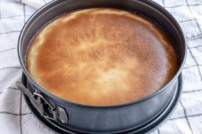 A baked cheesecake in a springform pan on a towel.