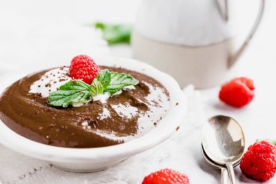 shiny chocolate pudding with fresh raspberries and whipped cream