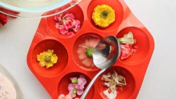 Pouring gelatinous mixture into a half moon shaped mold filled with edible flowers.