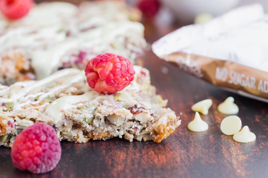 a keto granola bar topped with drizzled white chocolate and a raspberry laying on top