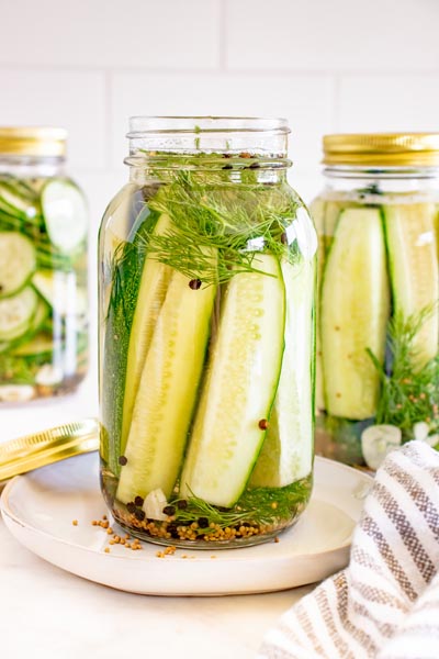 Homemade refrigerator dill pickle spears packed in a glass mason jar with fresh dill, garlic, mustard seeds, and peppercorns.
