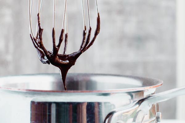 chocolate frosting dipping from a whisk