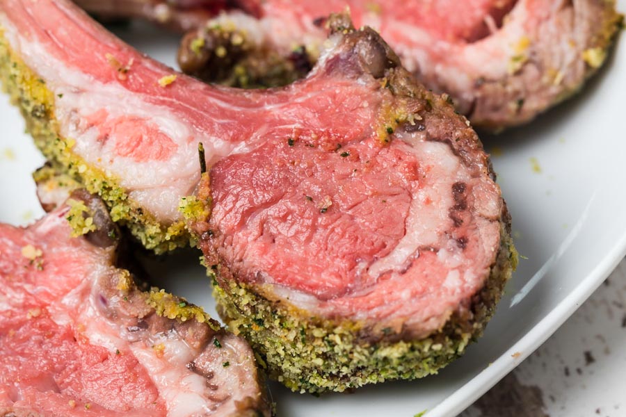 juicy lamb coated with a cheesy herb mixture on a white plate