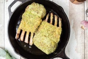 herb crusted lamb racks in a cast iron skillet