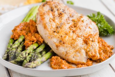 juicy romesco chicken and baked asparagus on a dinner plate