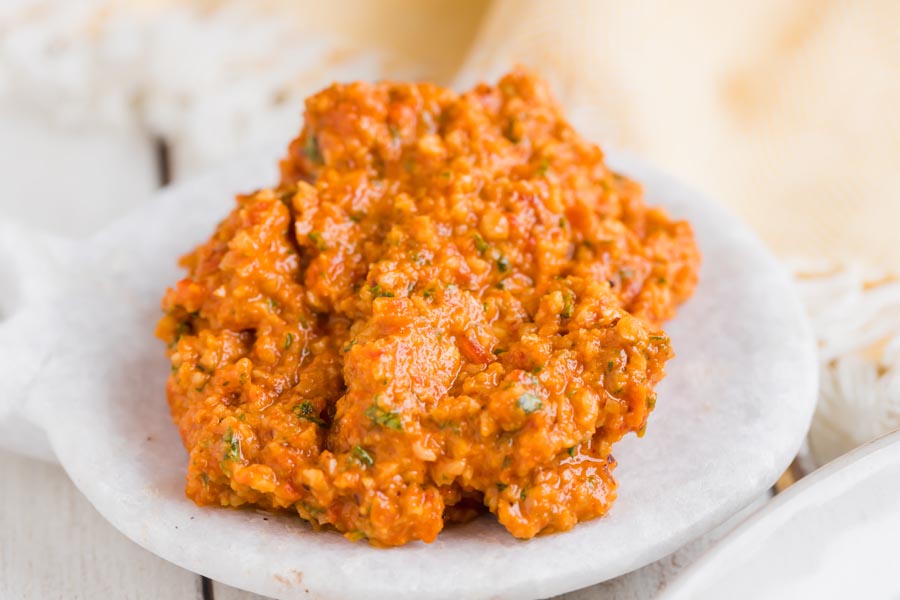 a white dish with red romesco sauce on it