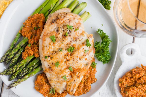 a plate with asparagus, chicken and romesco sauce all over