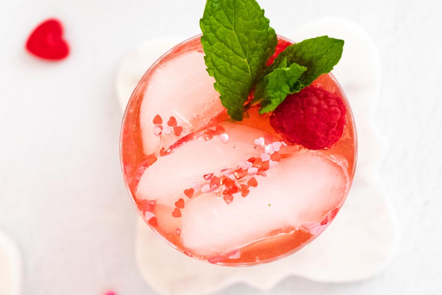 looking down into a cocktail glass with little hearts sprinkled on the ice cubes