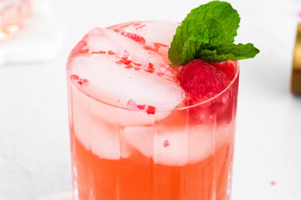 an icy rose cocktail with fresh mint and garnished with a raspberry