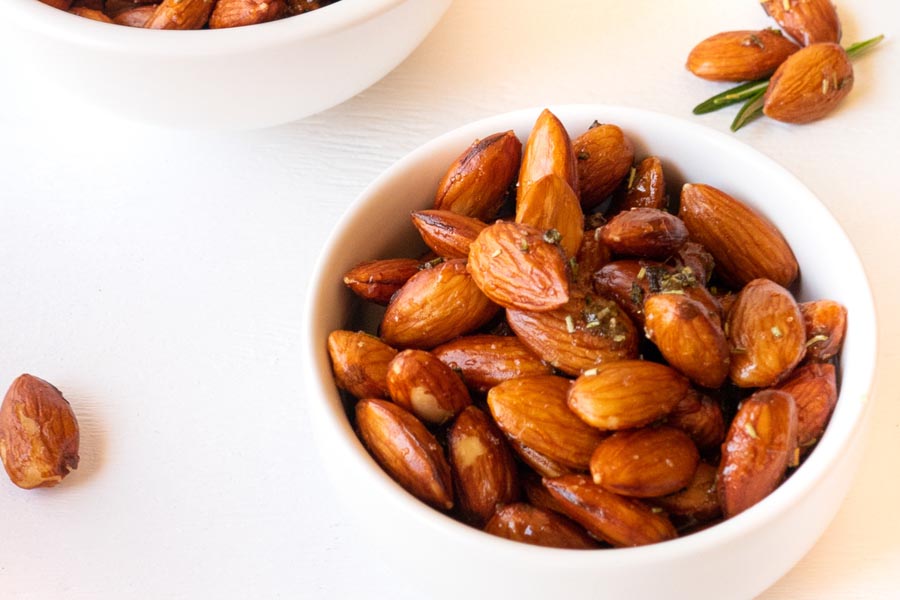 two bowls of seasoned almonds with nuts on the side