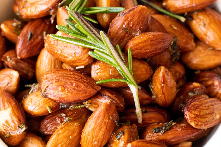 close up of roasted almond with a sprig of rosemary on top