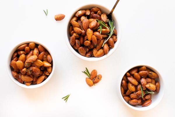 three small bowls of roasted almonds in an over head view
