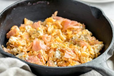 fluffy scrambled eggs in a skillet covered with dried dill