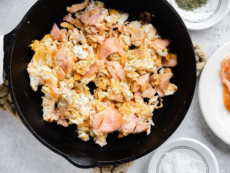 a cast iron skillet with smoked salmon scrambled eggs and more salmon