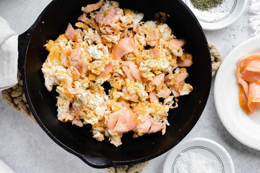 a cast iron skillet with smoked salmon scrambled eggs and more salmon