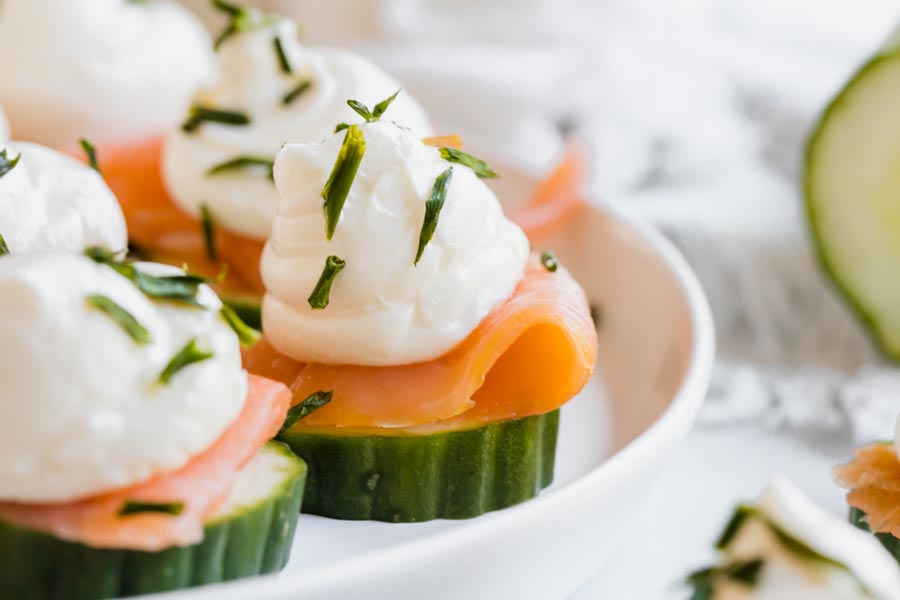 close up of a cucumber bite topped with salmon and cream cheese