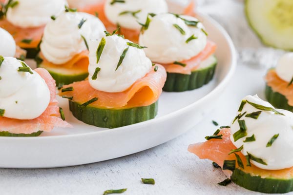 fresh cucumber topped with salmon and cream cheese on a white plate
