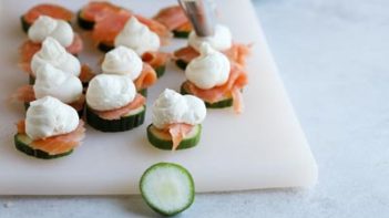 piping cream cheese on top of salmon cucumber bites