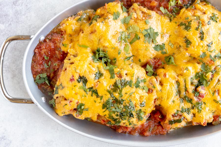 a skillet with baked salsa chicken topped with cheddar cheese and chopped cilantro