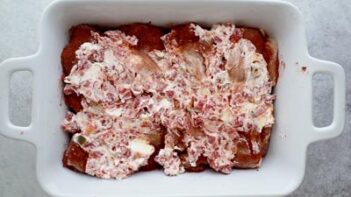 a mixture of cream cheese and rotel spread on top of raw chicken thighs