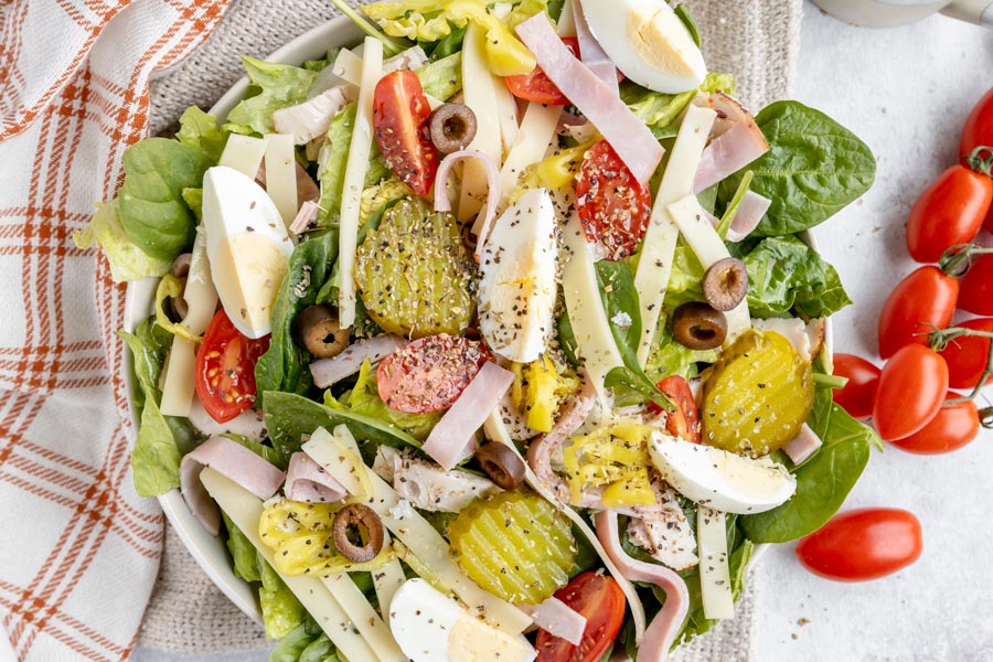 components of a sandwich assembled in salad form with grape tomatoes near by