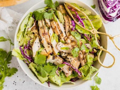 Sesame chicken salad with grilled chicken, lettuce, purple cabbage, cilantro and sesame seeds.