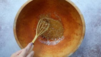 whisking dressing in a large wooden bowl