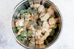 a bowl with broccoli, chicken chunks and spices in it
