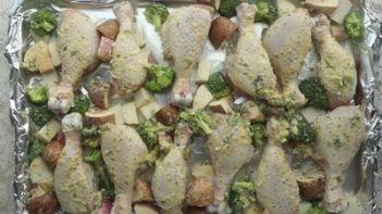 chicken legs on a baking sheet with broccoli, mushrooms and turnips basted with butter