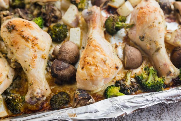 baked chicken and roasted vegetables on a baking tray lined with foil