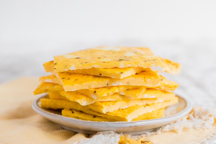 a stack of eggs on a plate with a yellow napkins