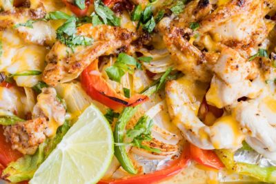 cheesy chicken fajitas close up with chopped cilantro and a lime wedge