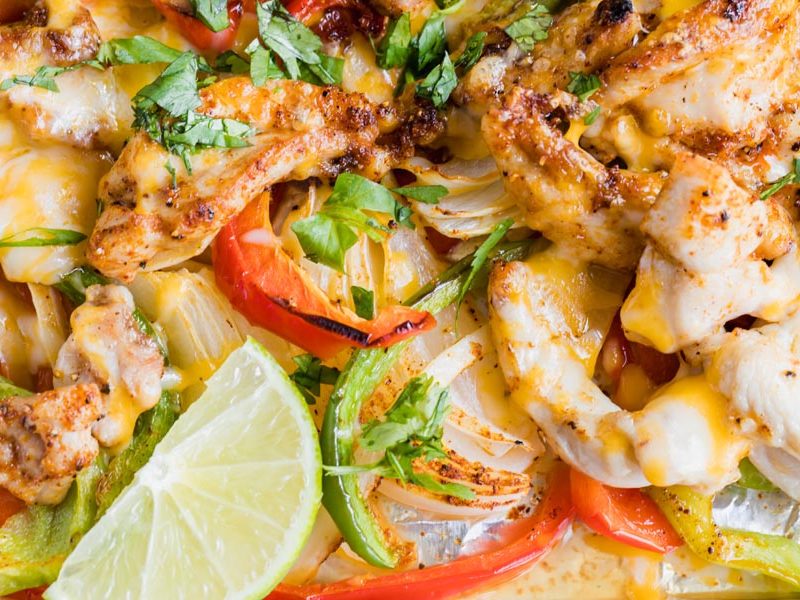cheesy chicken fajitas close up with chopped cilantro and a lime wedge
