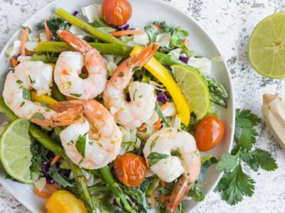 shrimp on top of a salad with bursting tomatoes and cilantro